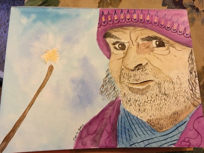 A wizard faces the viewer on the right side of the drawing, his cheeks and chin and visible neck covered in stubble. He seems to have mid-length hair or long sideburns. His face is lined, and he has a gruff expression on his face. His brown eyes almost glare at the viewer. He's wearing a purple knit hat with golden arrows pointing down detailed along the edge; it's pulled down over a wrinkled forehead. He may be wearing a blue plaid scarf, along with a purple jacket or robe - you only see it from the shoulders. A wand is held aloft, sloping in from the left side of the page - held aloft by the wizard, no doubt. The wand is brown, and there's a poof of golden magic floating above its tip.